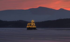 The winter sun sets behind the Hudson-Athens Lighthouse, bedecked in holiday lights. Used with permission from HALPS.